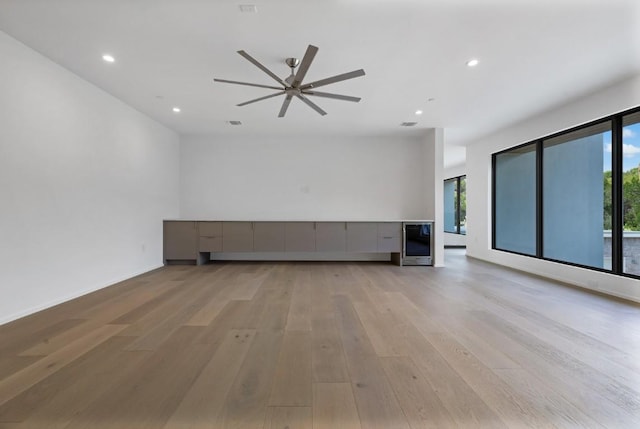 unfurnished living room with beverage cooler, recessed lighting, and light wood-style flooring