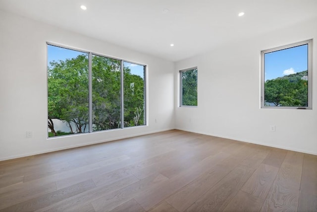 spare room with recessed lighting, baseboards, and wood finished floors