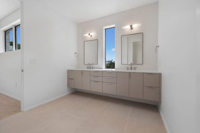 bathroom featuring tile patterned flooring, double vanity, baseboards, and a sink