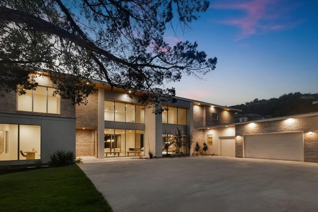 contemporary house with stucco siding, stone siding, concrete driveway, and an attached garage