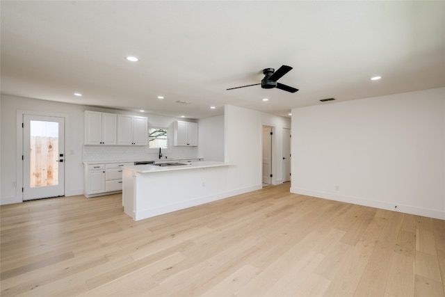 kitchen featuring light wood-type flooring, tasteful backsplash, ceiling fan, kitchen peninsula, and white cabinets