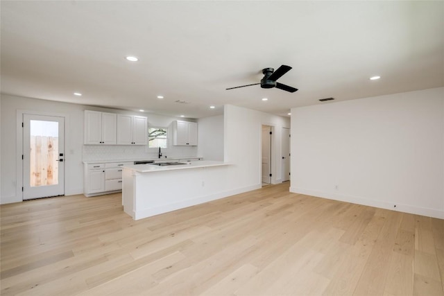 kitchen featuring a wealth of natural light, light countertops, decorative backsplash, white cabinets, and light wood-type flooring