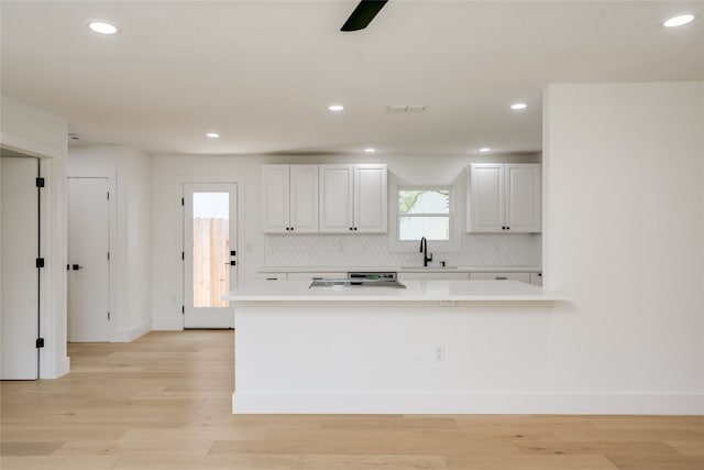 kitchen featuring light hardwood / wood-style flooring, tasteful backsplash, white cabinets, range, and sink