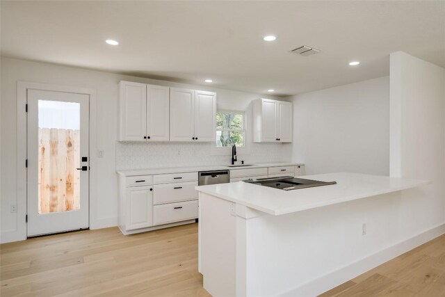 kitchen with white cabinetry, backsplash, sink, and light hardwood / wood-style flooring