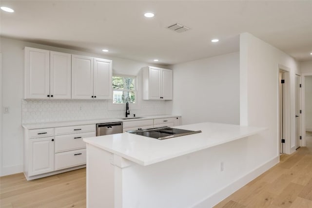 kitchen featuring light wood finished floors, visible vents, backsplash, and stainless steel dishwasher