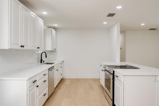 kitchen with sink, light wood-type flooring, decorative backsplash, white cabinetry, and stainless steel appliances