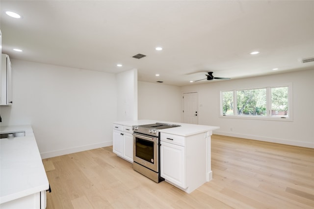 kitchen with sink, white cabinetry, light wood-type flooring, stainless steel range, and ceiling fan