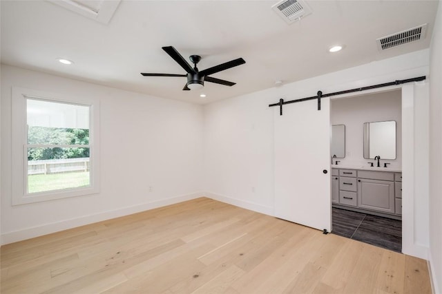 1928 Miles Ave Unit 1, Austin, TX 78745 - unfurnished bedroom featuring a barn door, visible vents, light wood finished floors, and recessed lighting