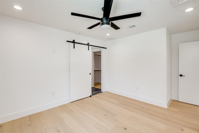 unfurnished room with recessed lighting, a barn door, light wood-style floors, ceiling fan, and baseboards