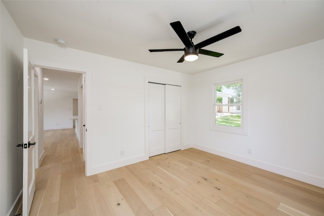 unfurnished bedroom with ceiling fan, light wood-type flooring, and a closet