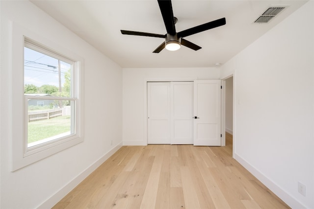 unfurnished bedroom featuring multiple windows, a closet, light hardwood / wood-style flooring, and ceiling fan