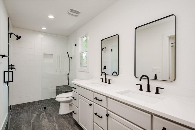 bathroom featuring tile patterned flooring, toilet, dual vanity, and a shower with shower door