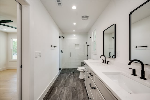 bathroom featuring double sink vanity, wood-type flooring, toilet, and an enclosed shower