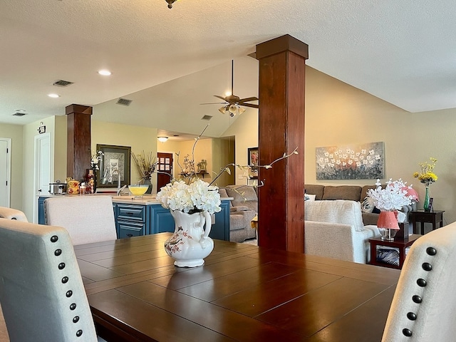 dining space with a textured ceiling, ceiling fan, ornate columns, and lofted ceiling