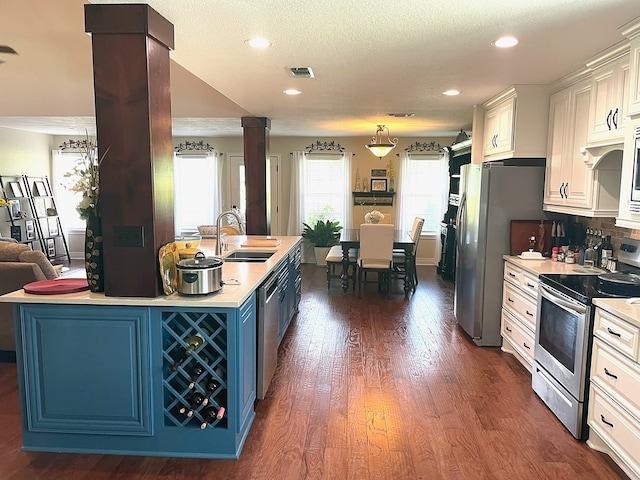 kitchen featuring sink, appliances with stainless steel finishes, dark hardwood / wood-style floors, blue cabinetry, and white cabinets