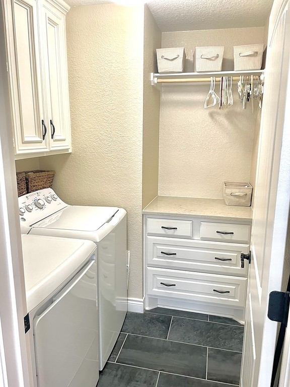 washroom featuring dark tile patterned flooring, a textured ceiling, cabinets, and independent washer and dryer