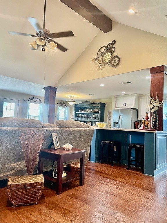 living room with ceiling fan, beam ceiling, light hardwood / wood-style floors, and high vaulted ceiling