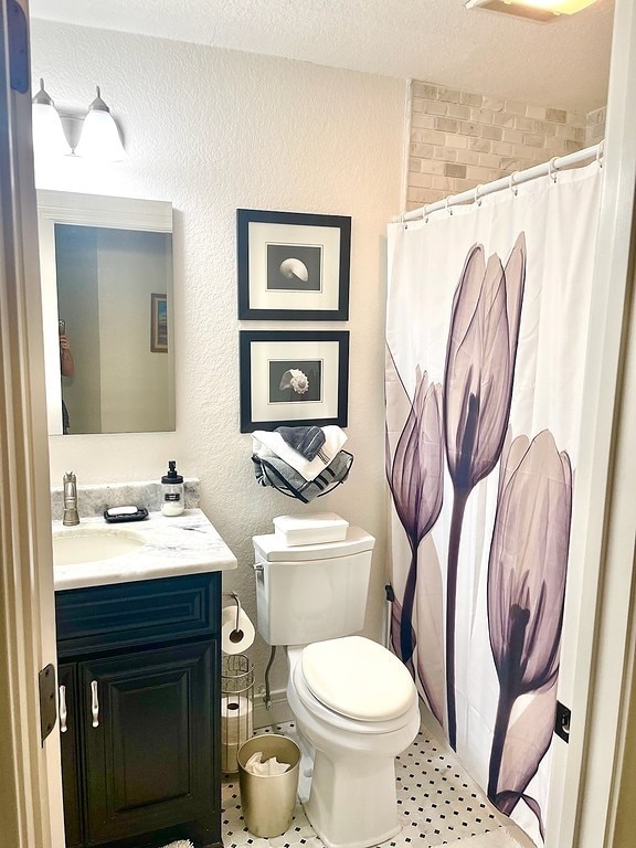 bathroom featuring toilet, a textured ceiling, tile patterned flooring, and vanity