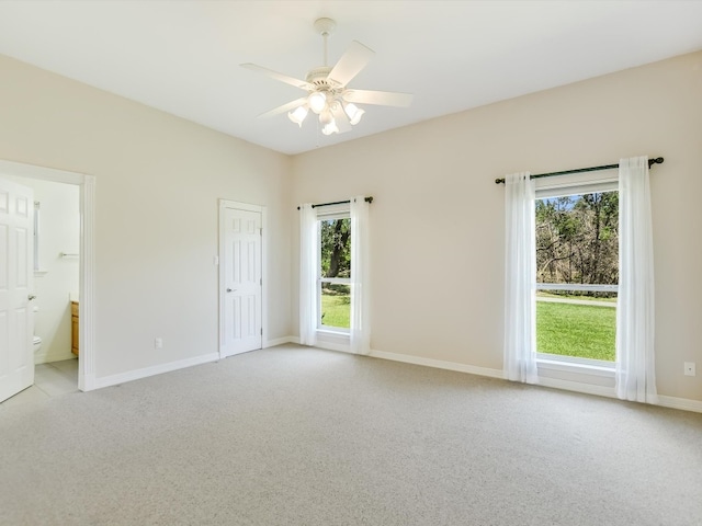 interior space featuring multiple windows, light colored carpet, and ensuite bath