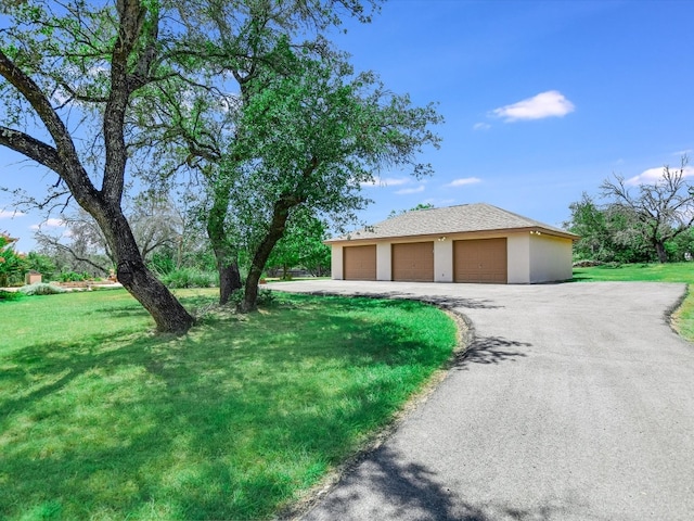 view of side of home featuring a garage, an outbuilding, and a lawn