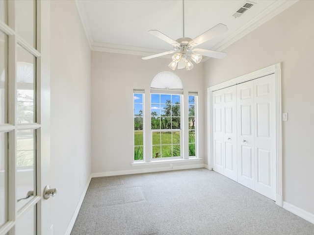 unfurnished bedroom featuring ceiling fan, ornamental molding, a closet, and carpet flooring