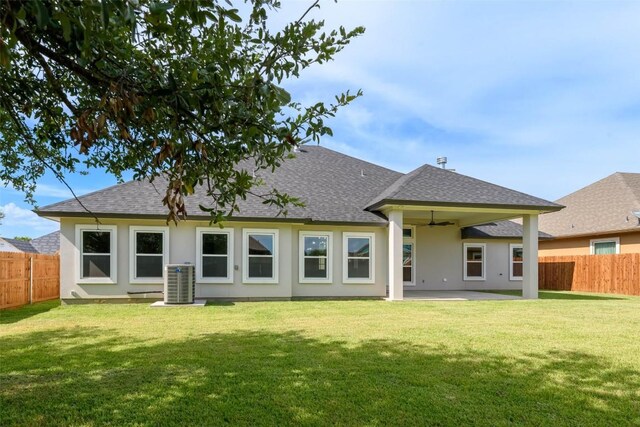 back of house featuring stucco siding, a fenced backyard, central AC unit, and a yard