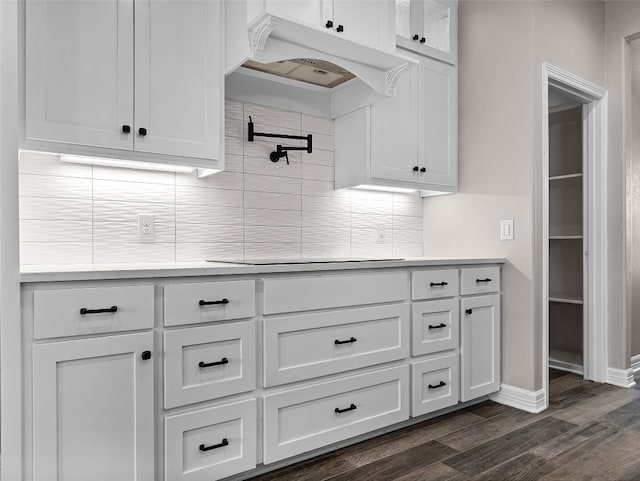 kitchen featuring decorative backsplash, premium range hood, and white cabinets