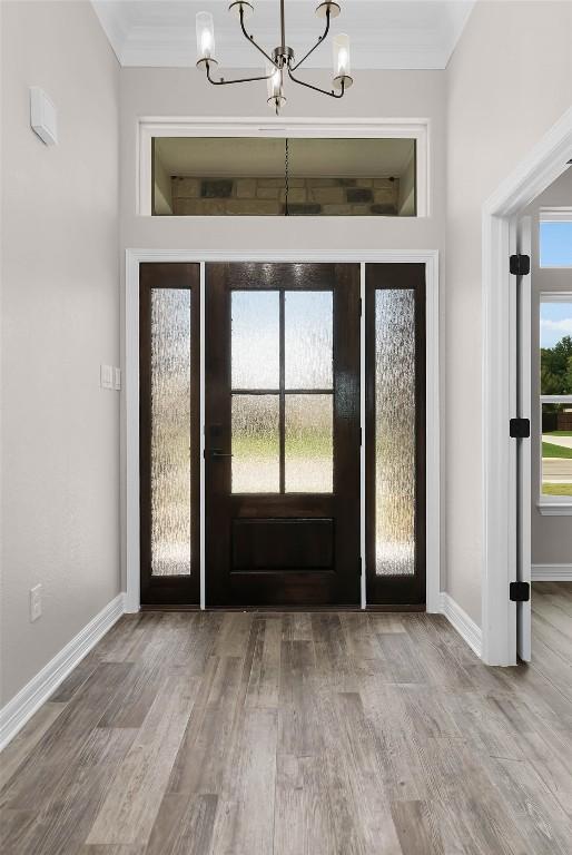 entrance foyer with a notable chandelier, crown molding, and hardwood / wood-style floors