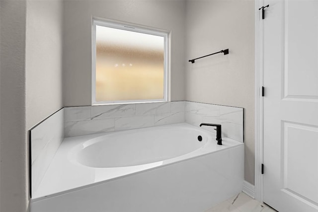 full bathroom featuring marble finish floor and a garden tub