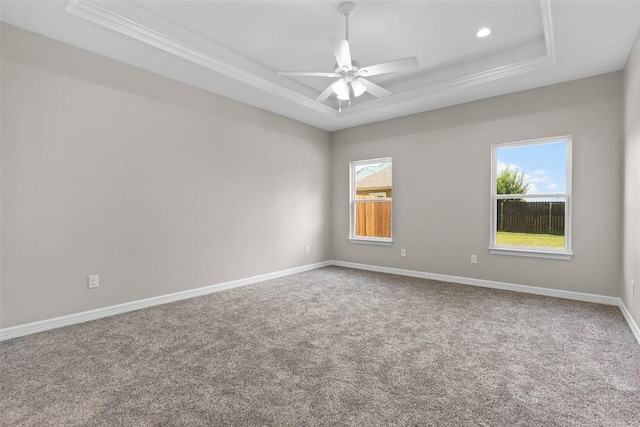 carpeted empty room featuring crown molding, a raised ceiling, ceiling fan, and baseboards