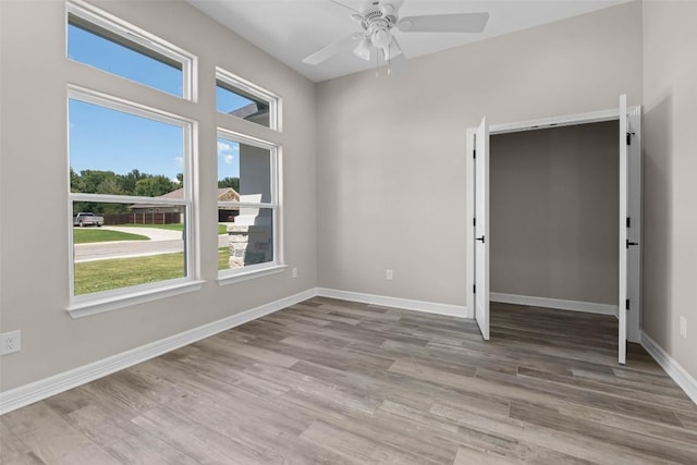 empty room featuring baseboards, a ceiling fan, and light wood-style floors