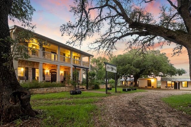 back house at dusk with a yard and a balcony