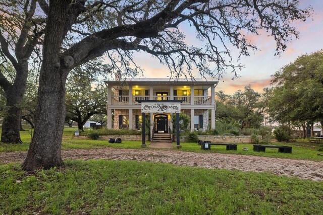 view of front of property featuring a lawn and a balcony
