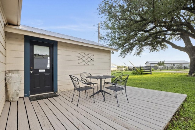 wooden deck featuring outdoor dining space, a yard, and fence