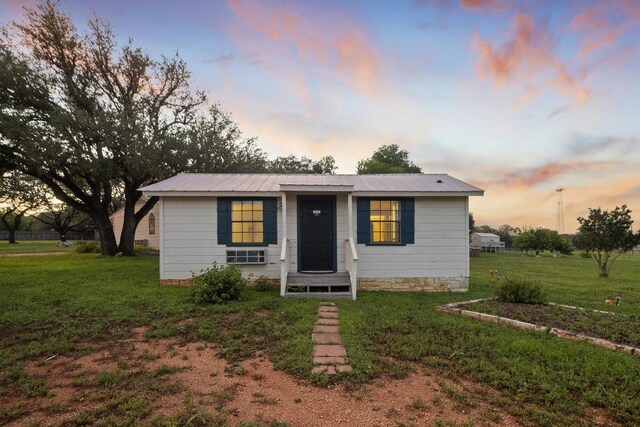 bungalow-style house featuring metal roof and a lawn