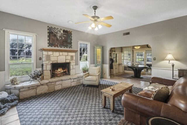 tiled living area with visible vents, ceiling fan, and a fireplace