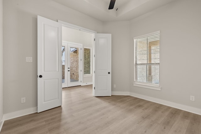 unfurnished room featuring light wood-style floors, baseboards, a ceiling fan, and french doors