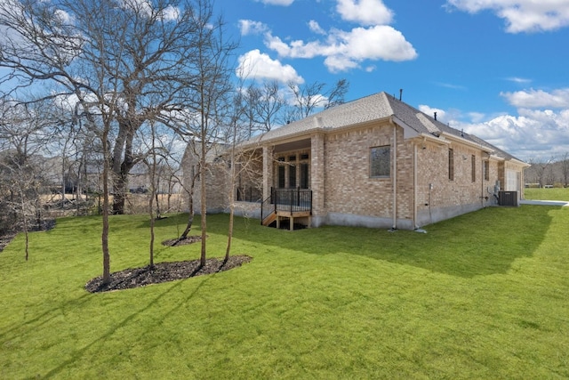 view of side of property with a yard, central AC, and brick siding