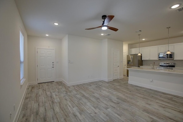 unfurnished living room featuring light wood-type flooring, ceiling fan, and sink