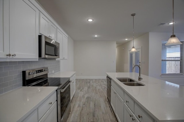 kitchen featuring white cabinetry, sink, decorative light fixtures, and appliances with stainless steel finishes