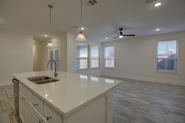 kitchen with pendant lighting, white cabinetry, a kitchen island with sink, and sink