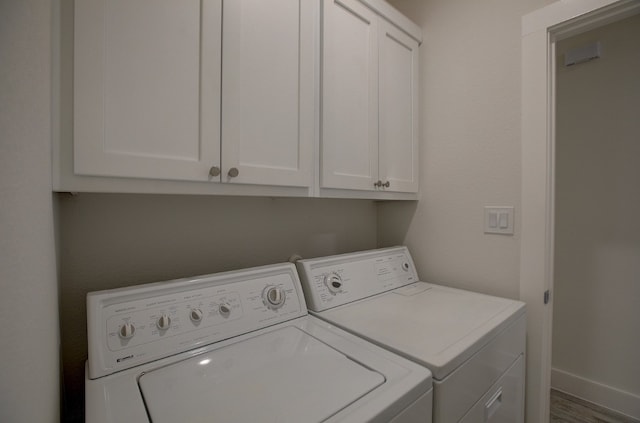 laundry room with cabinets, wood-type flooring, and washing machine and clothes dryer