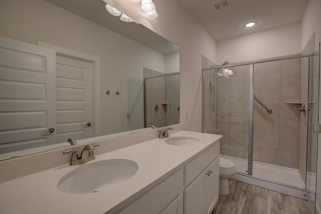 bathroom featuring hardwood / wood-style flooring, vanity, toilet, and walk in shower