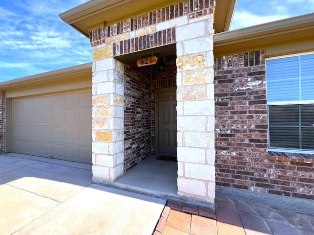 doorway to property featuring concrete driveway, brick siding, and an attached garage