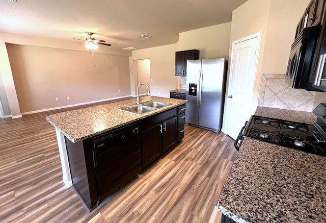 kitchen featuring black appliances, a sink, a kitchen island with sink, and light wood-style floors