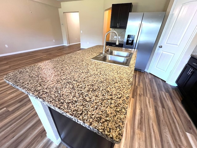 kitchen featuring sink, dark wood-type flooring, light stone countertops, and stainless steel refrigerator with ice dispenser