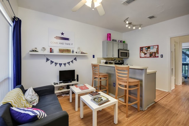 living room with light wood-type flooring, track lighting, and ceiling fan