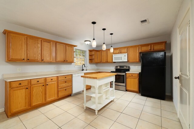 kitchen with light tile patterned flooring, butcher block counters, white appliances, a kitchen island, and hanging light fixtures