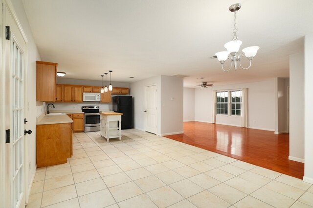 kitchen with light wood-type flooring, stainless steel electric range oven, black fridge, a center island, and hanging light fixtures