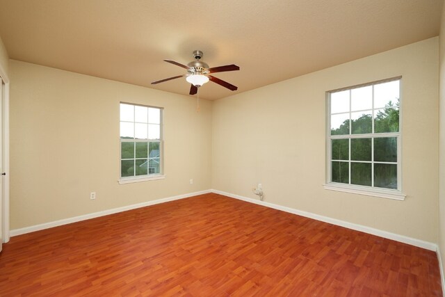 empty room featuring a wealth of natural light, ceiling fan, and hardwood / wood-style floors